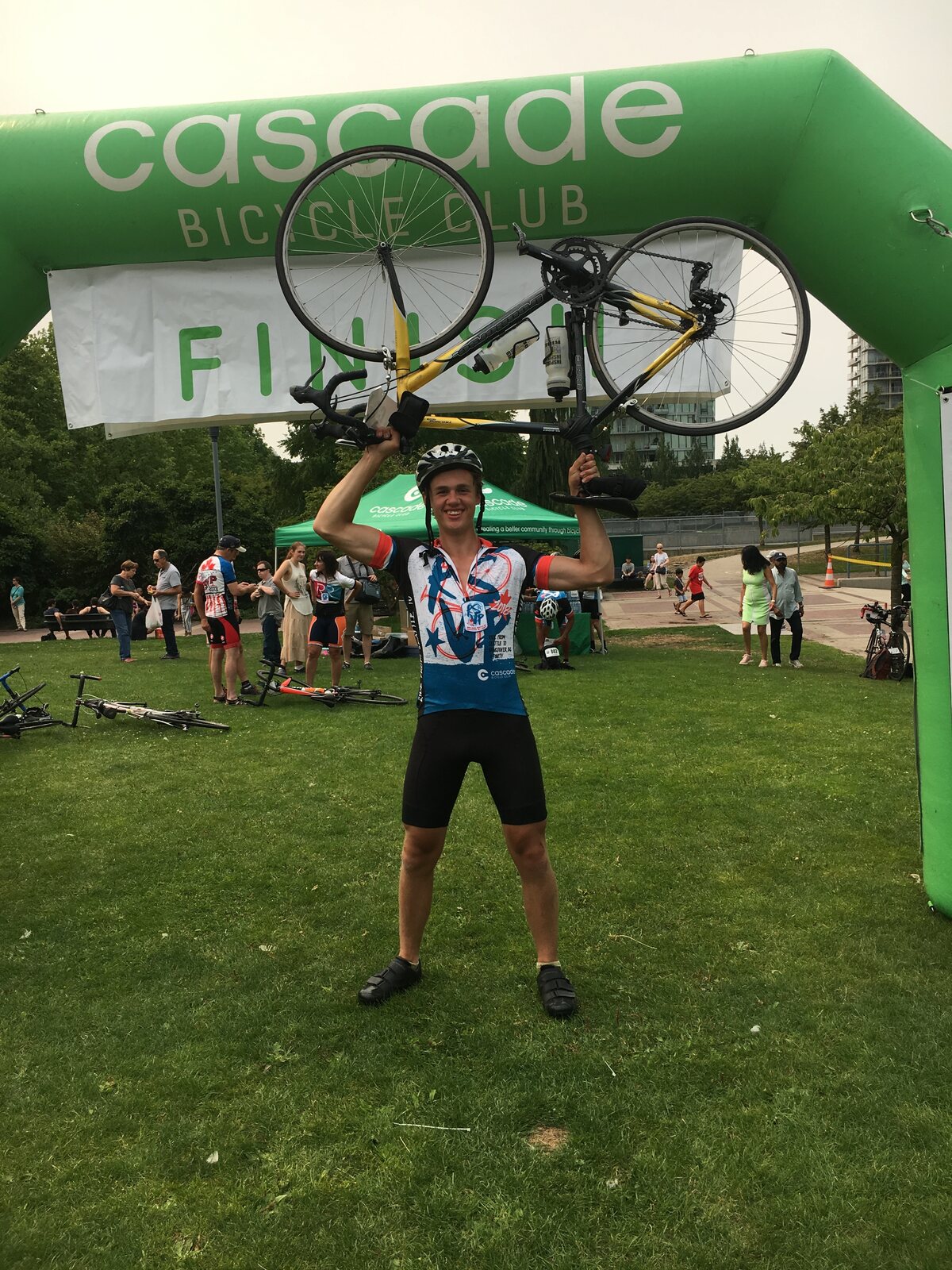 Matthew lifting his bike overhead at a Cascade Bicycle Club finish line