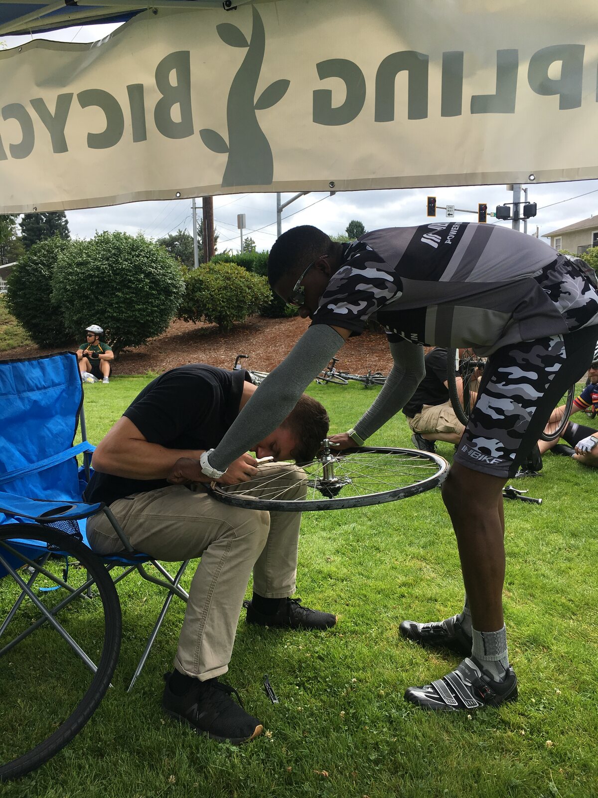Teen Matthew truing a wheel for another rider at a race — running his own traveling mechanic shop